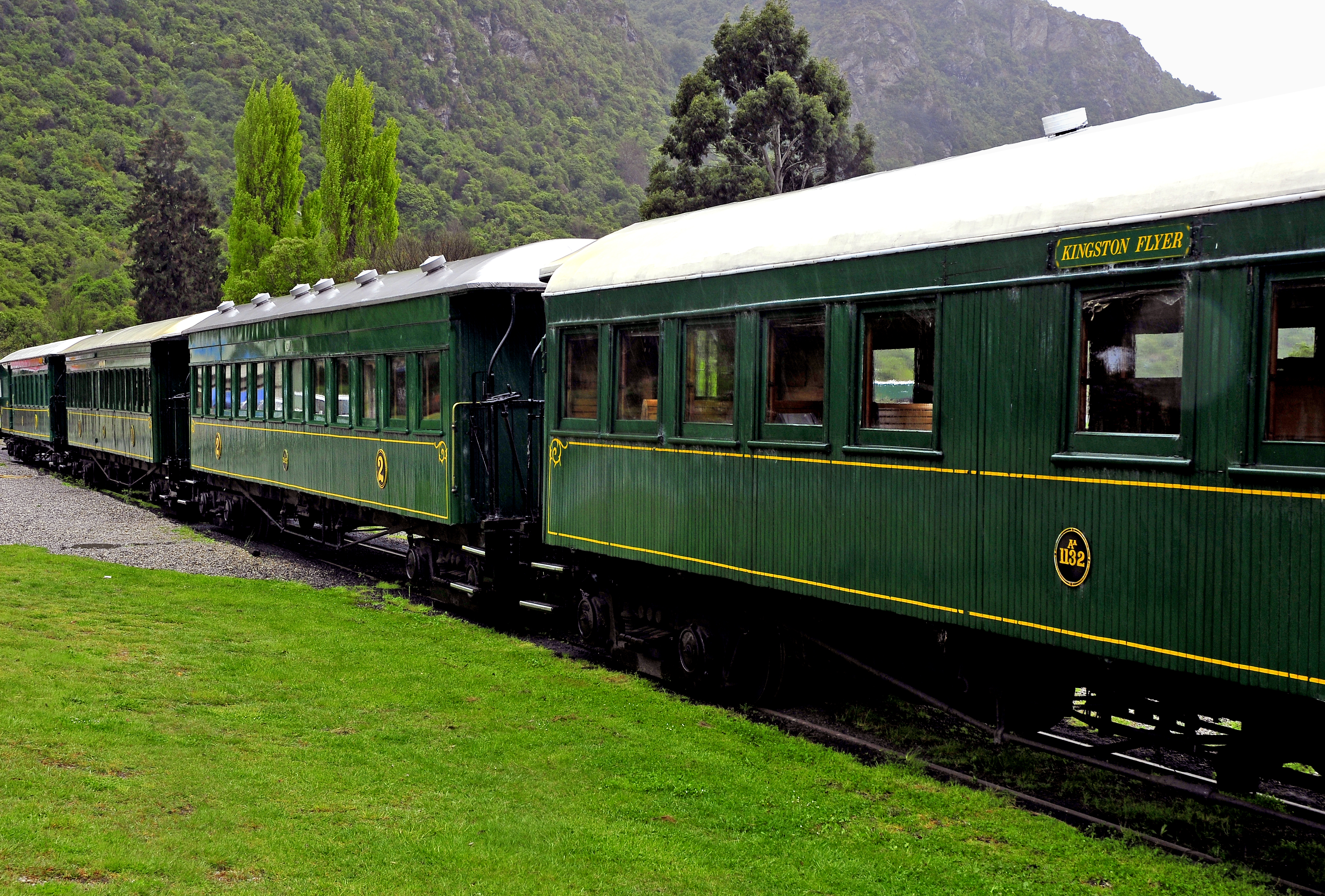 The Kingston Flyer’s green heritage carriages standing on the branch line at Kingston, lake hills behind.