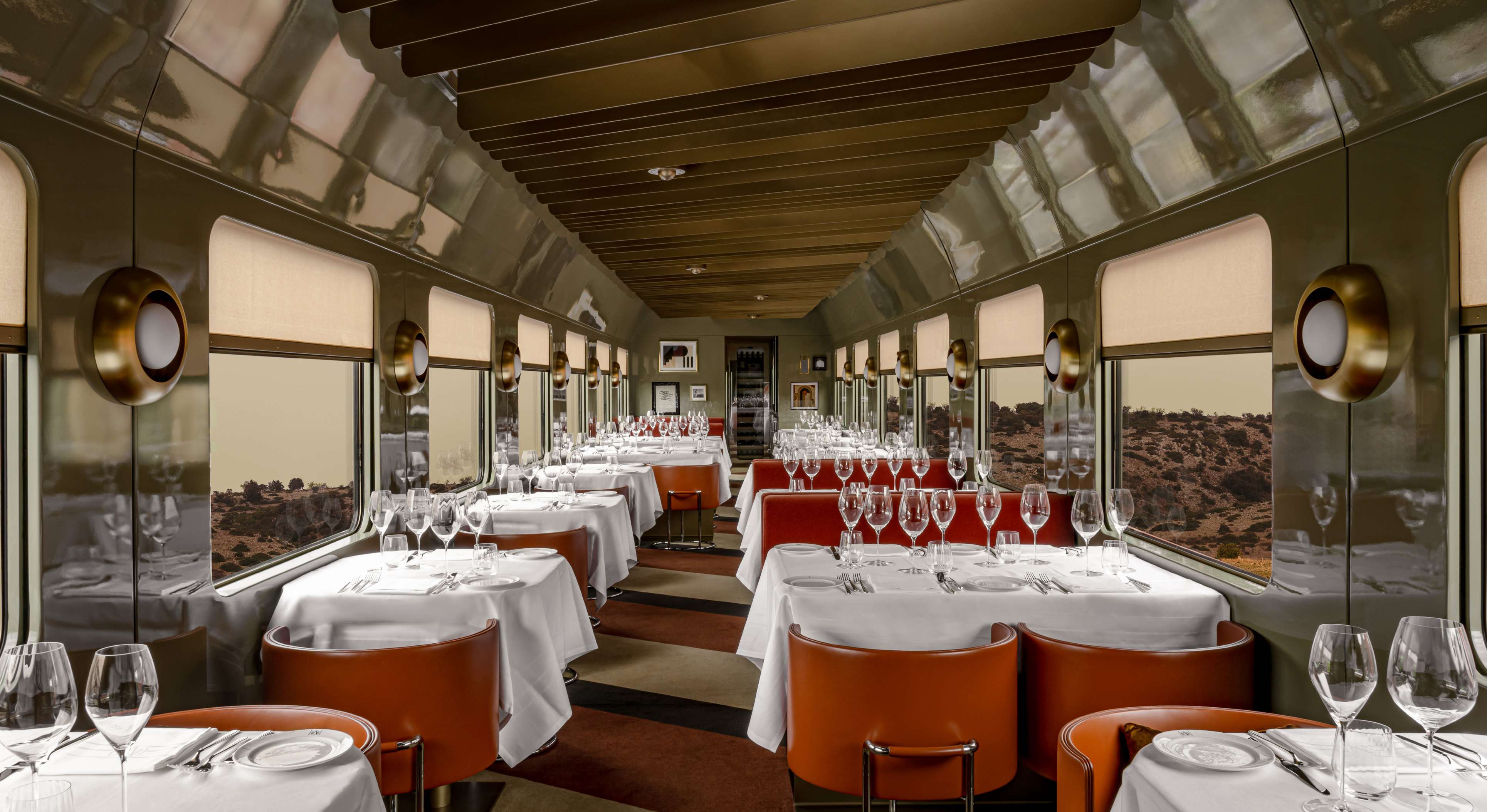 The dining car aboard La Dolce Vita Orient Express, set with white tablecloths and orange leather chairs.