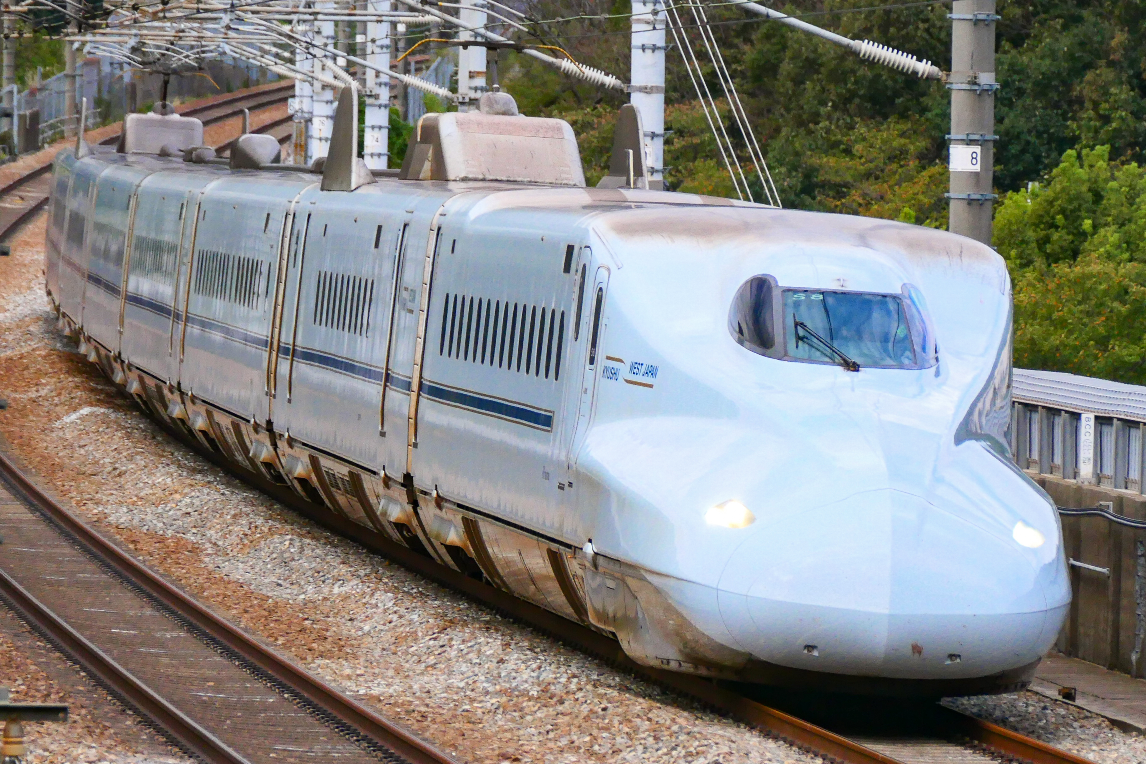 An N700-7000 series Sakura Shinkansen running in daylight.
