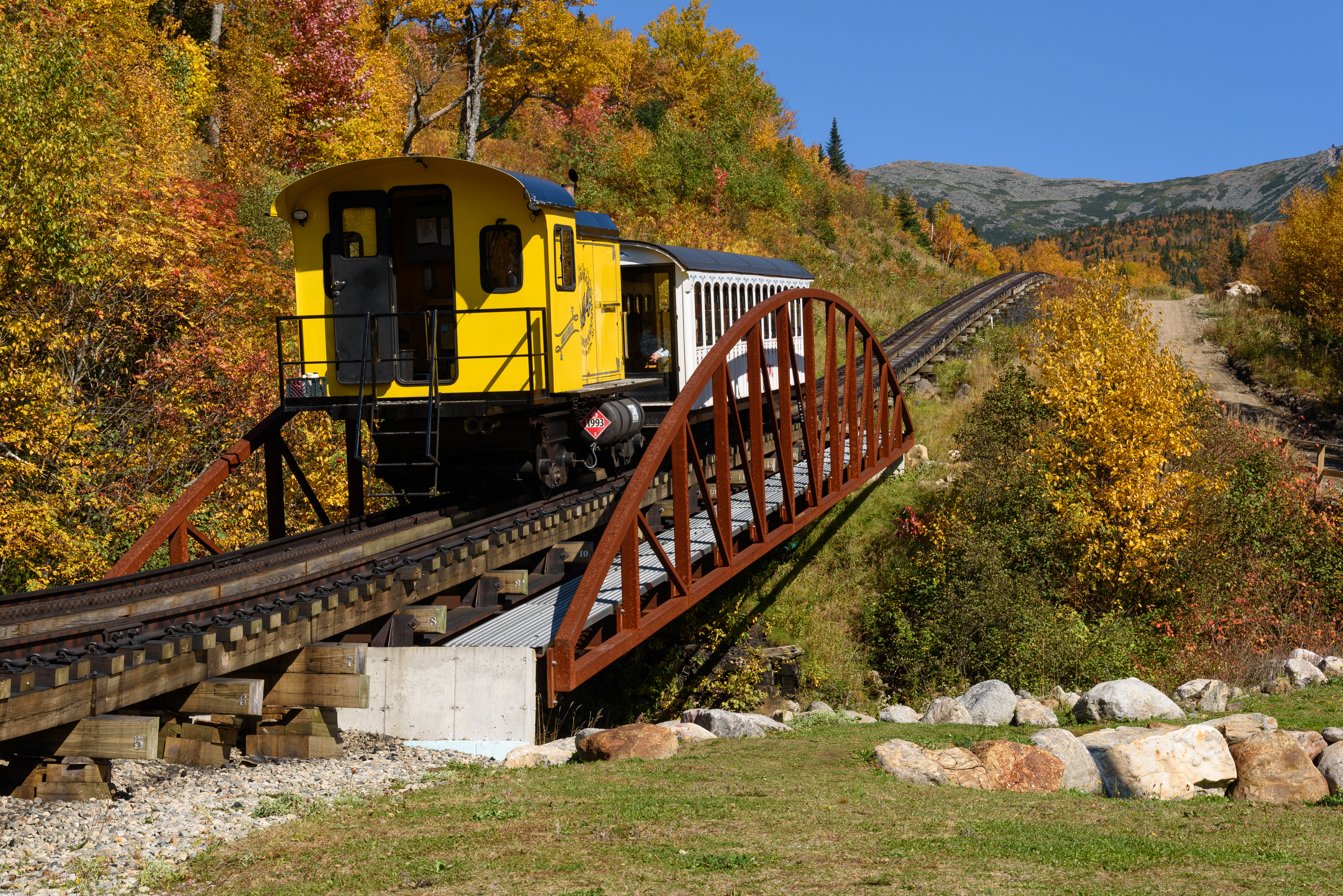 A Mount Washington Cog Railway train climbing a trestle through autumn colour.