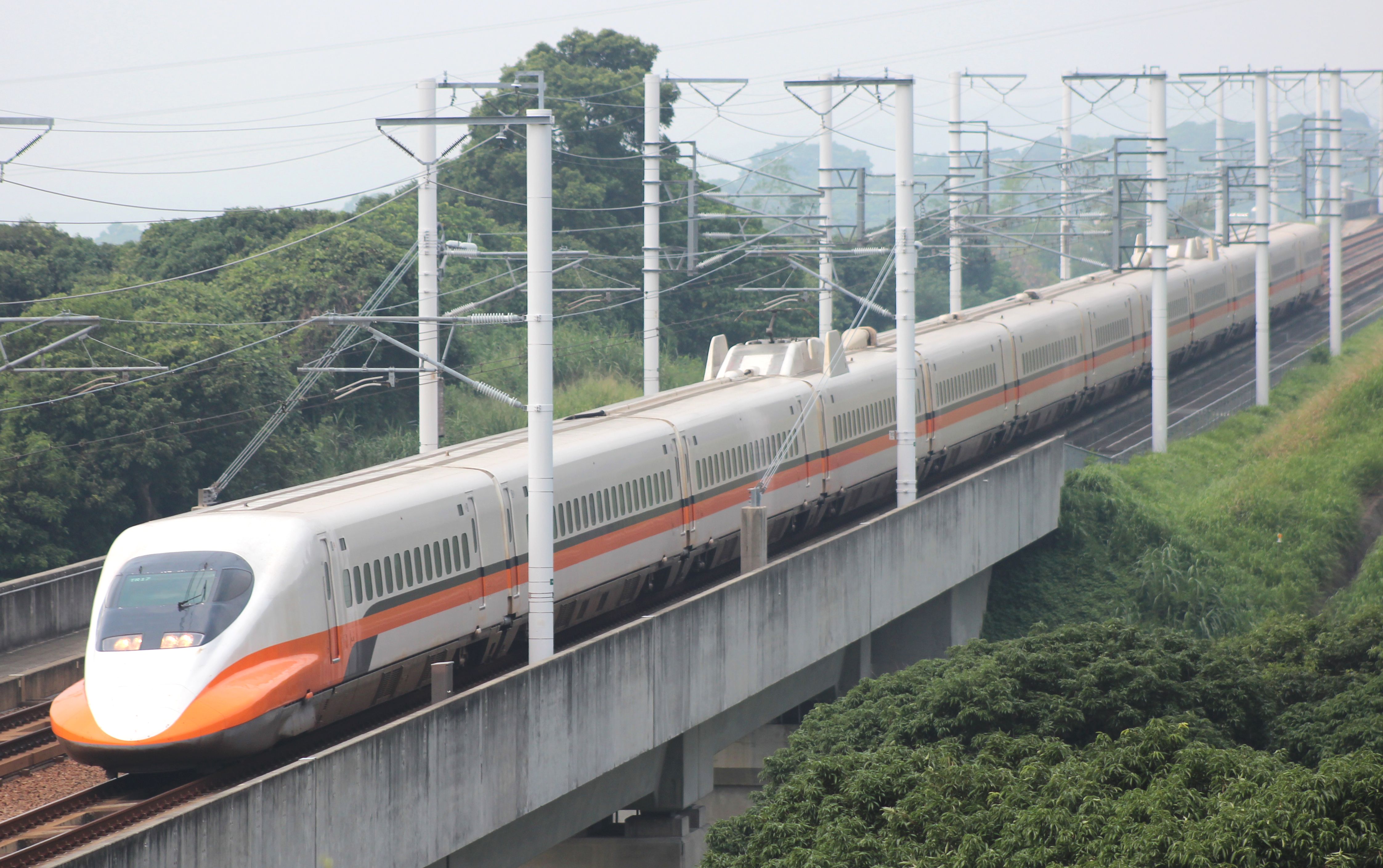 A Taiwan High Speed Rail 700T train on the elevated main line through green hills.