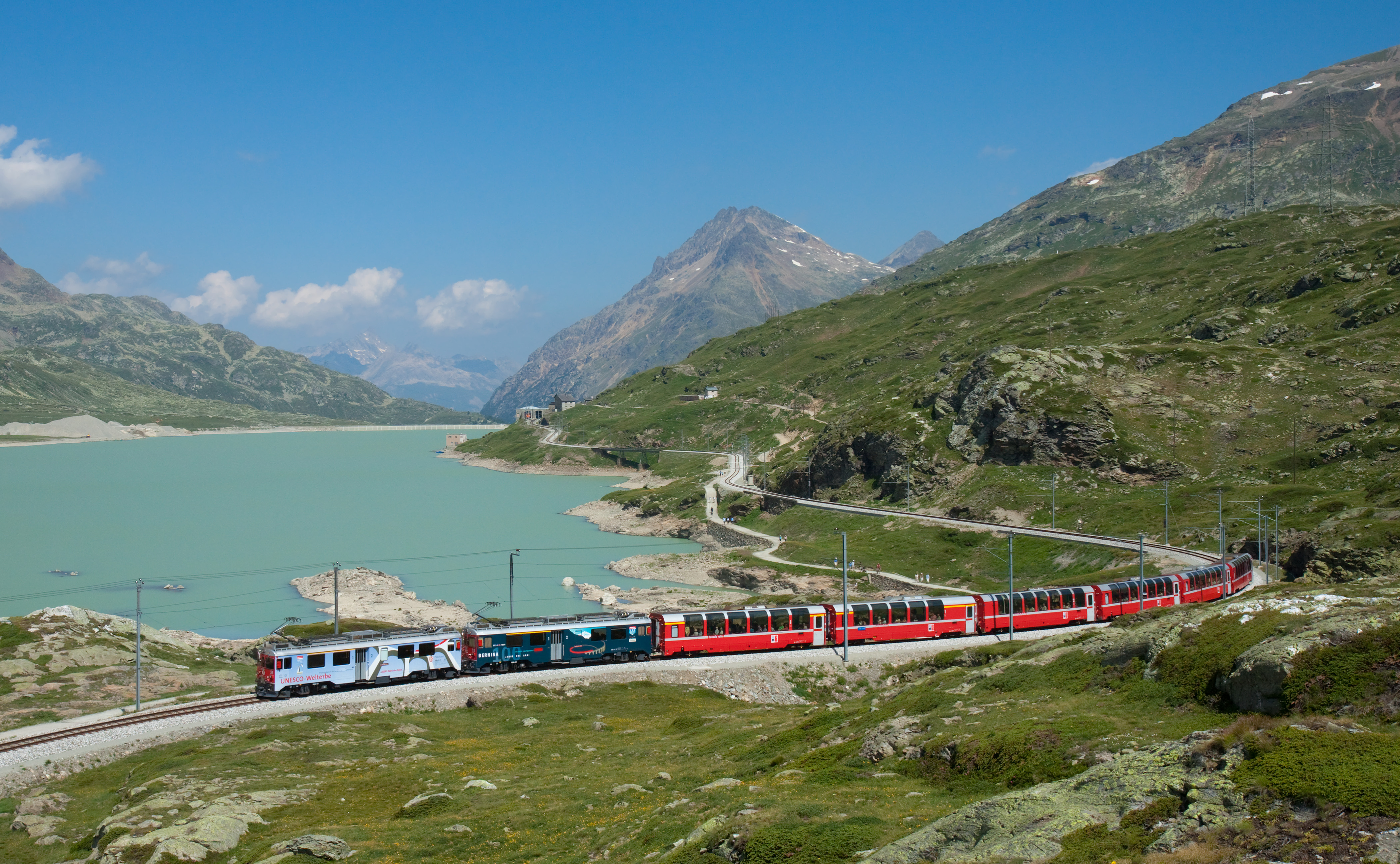A Bernina Express train beside Lago Bianco on the Bernina railway.