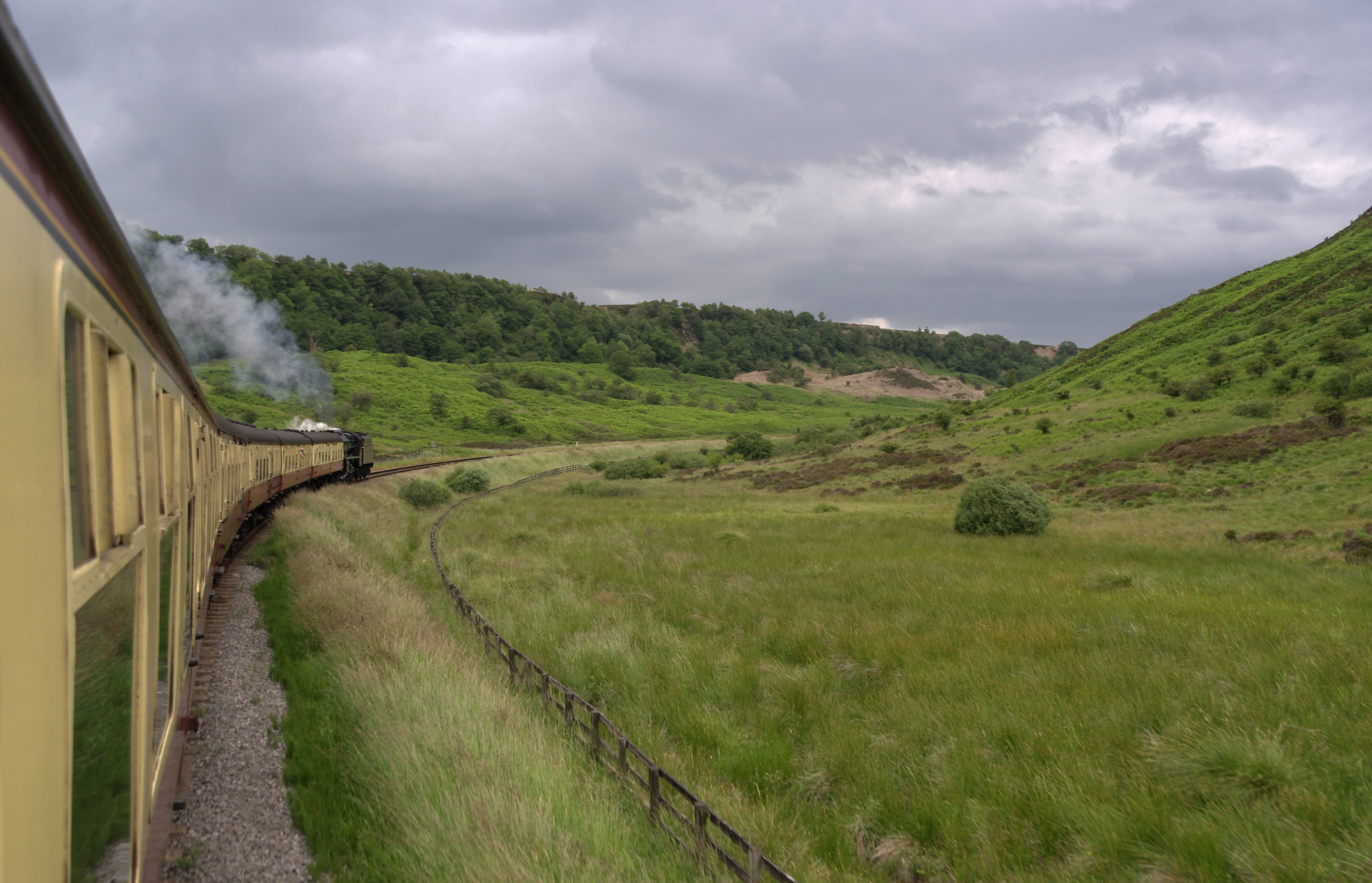 A preserved steam locomotive hauls a North Yorkshire Moors Railway train across the moorland.