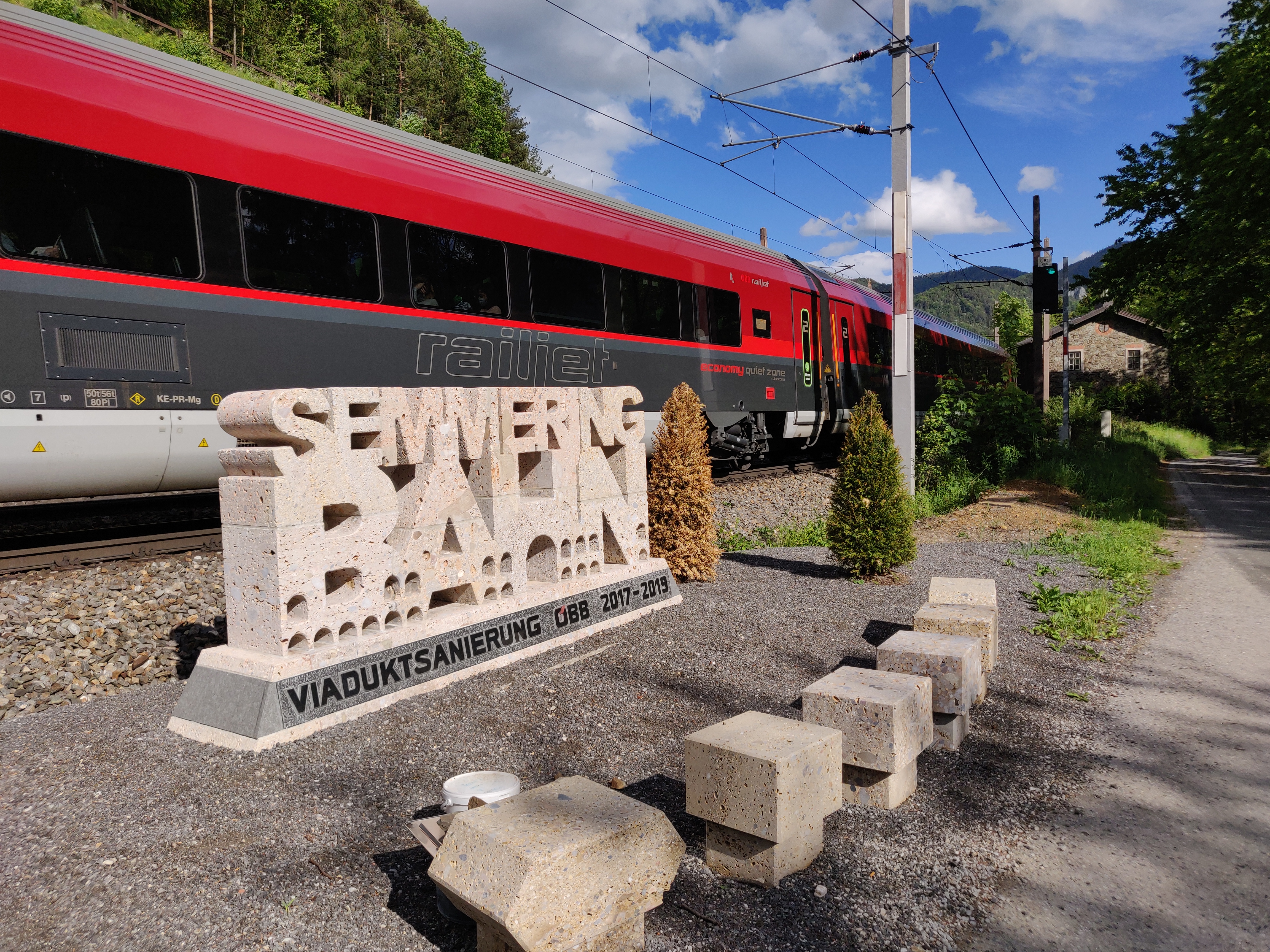 An ÖBB Railjet train passes a Semmering railway viaduct restoration monument.