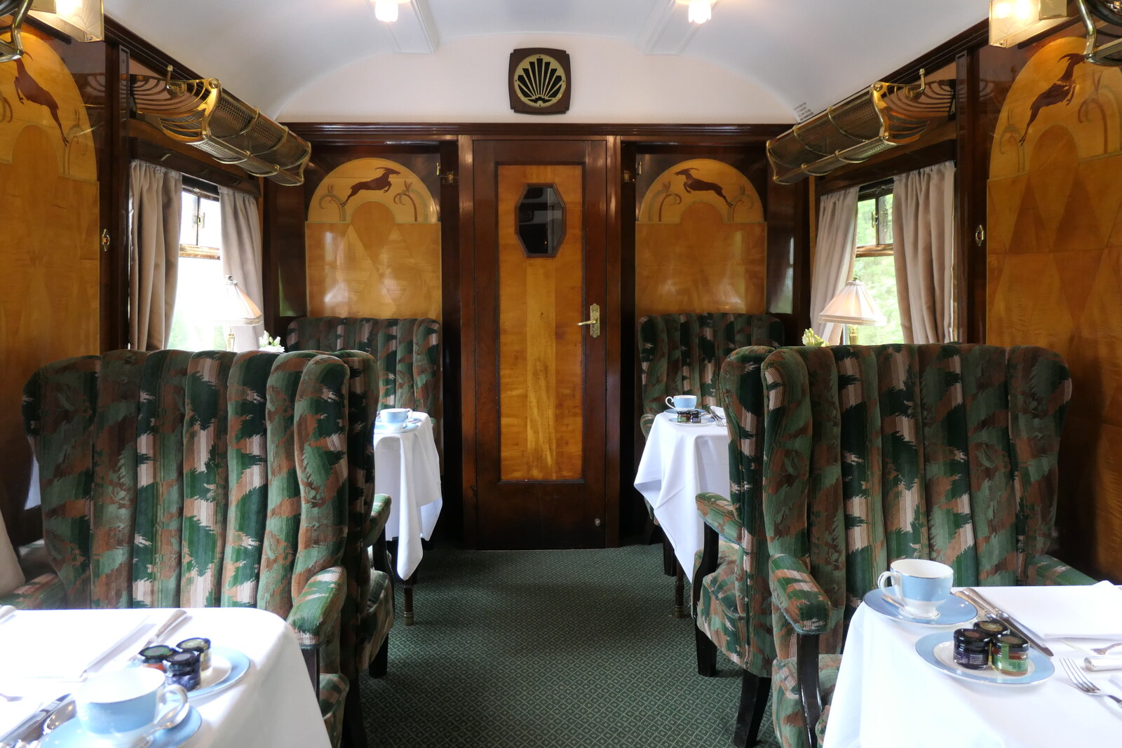 Inside British Pullman car Vera: marquetry panels, wing-back armchairs and tables laid with white linen and china.