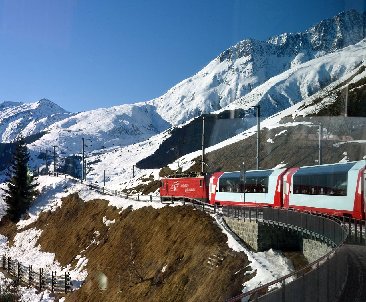 Glacier Express travelling through a snowy Alpine landscape in Switzerland.