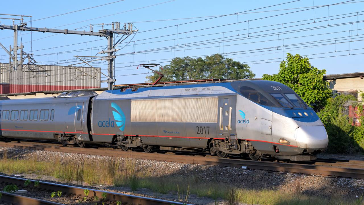 An Amtrak Acela trainset runs through the Northeast Corridor in daylight.