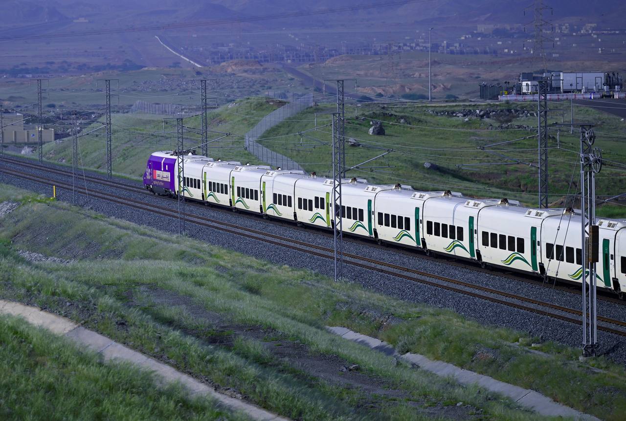 A Haramain high-speed train running through open country between Makkah and Madinah.
