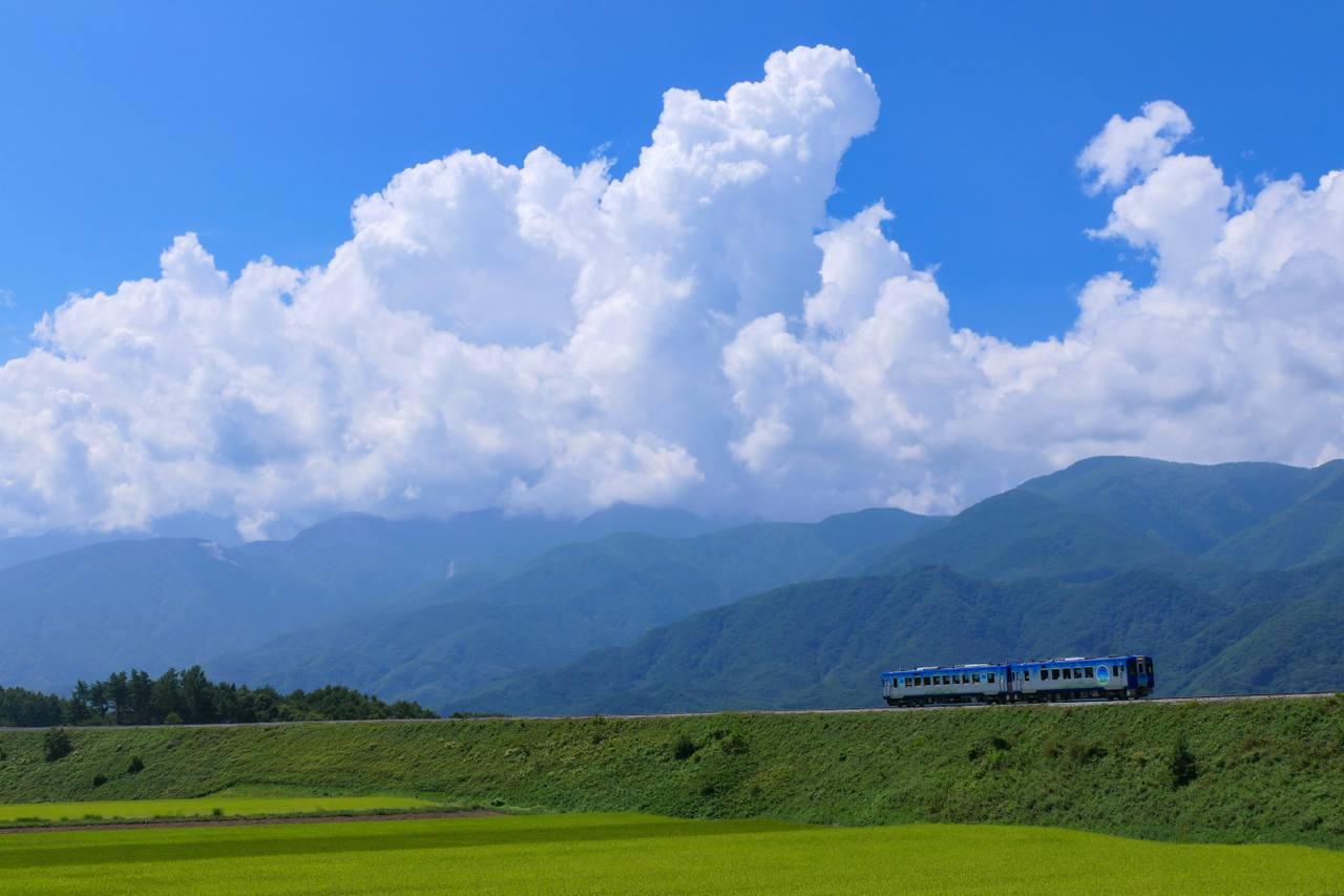 HIGH RAIL 1375 crossing the highland Koumi Line beneath summer clouds.