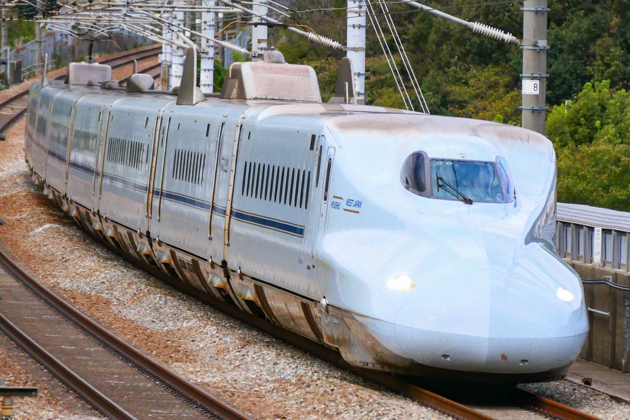 An N700-7000 series Sakura Shinkansen running in daylight.