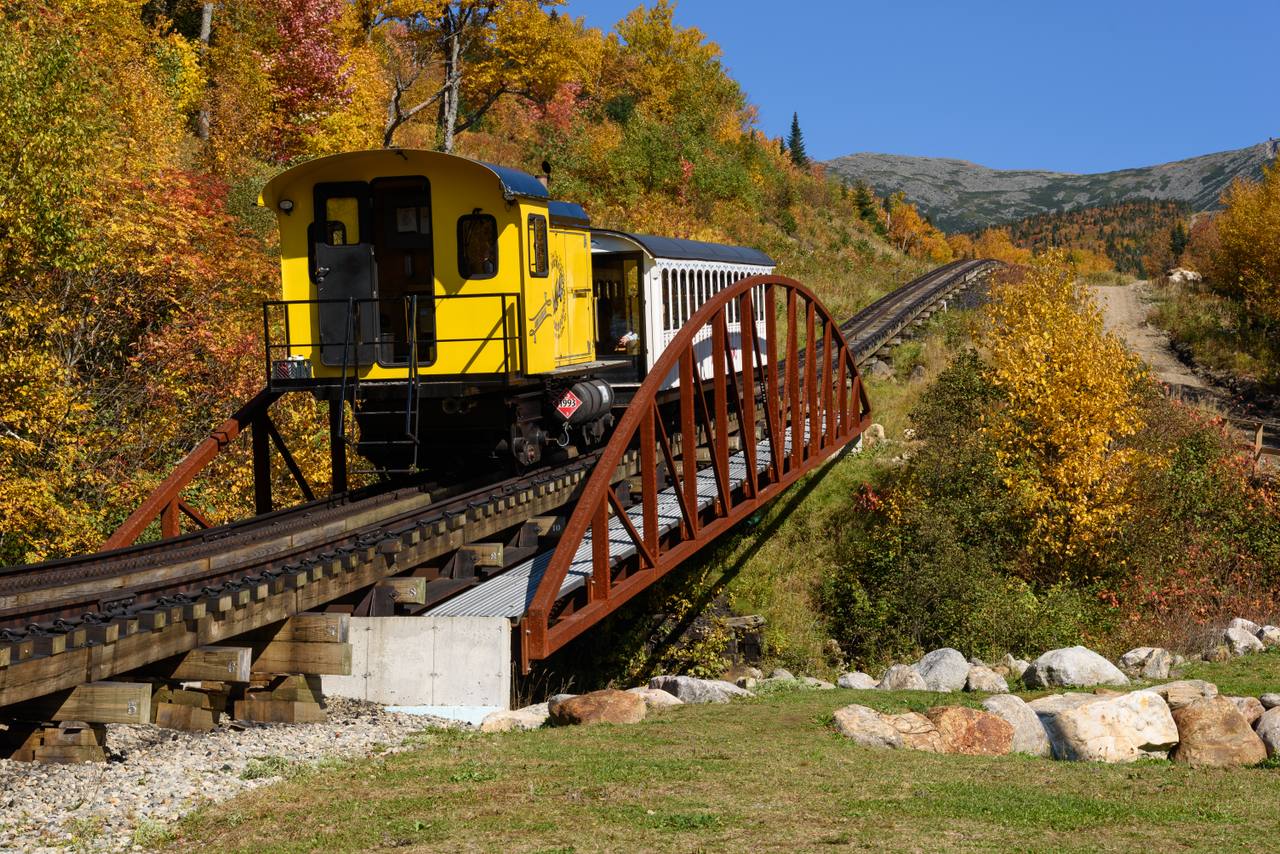 A Mount Washington Cog Railway train climbing a trestle through autumn colour.