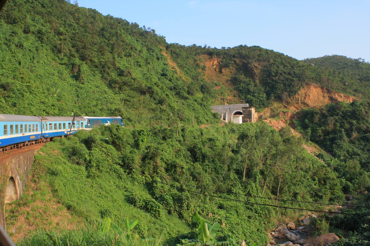 A Reunification Express train curves along the forested coastal mountains of central Vietnam.