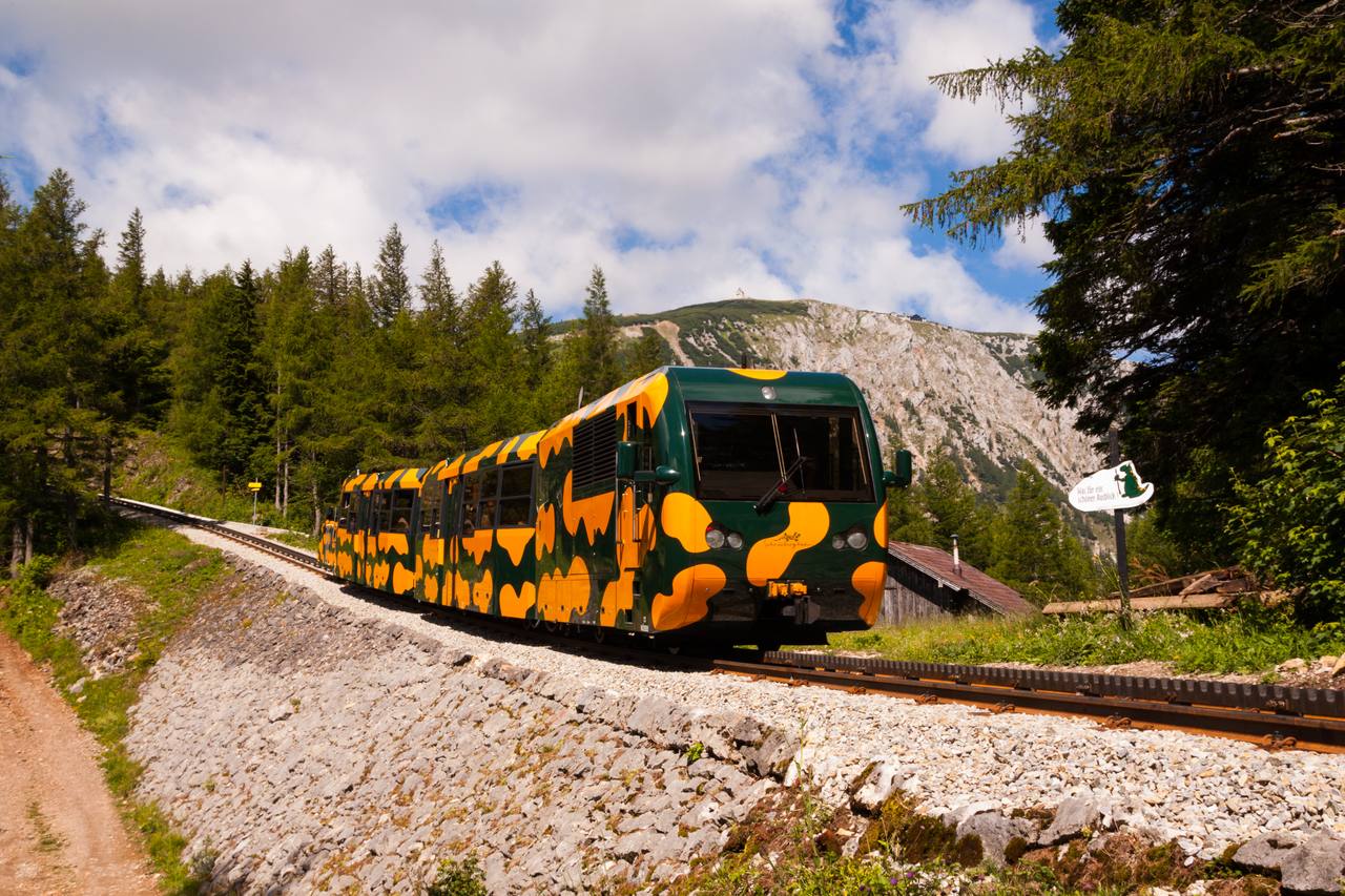A Schneebergbahn train climbing the open mountainside above Baumgartner.
