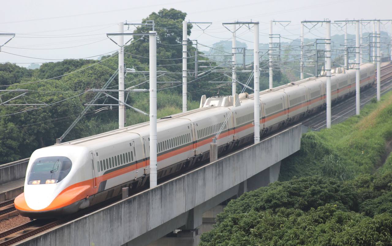 A Taiwan High Speed Rail 700T train on the elevated main line through green hills.