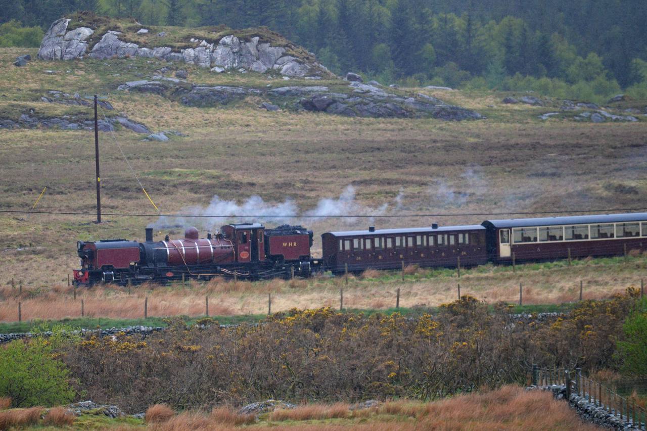A Welsh Highland Railway Garratt locomotive hauling its train through the Snowdonia landscape.